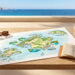 Vue d'une carte colorée des Baléares, lunettes, carnet sur table en bois devant mer et falaises ensoleillées.
