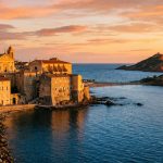 Vue panoramique d'Ajaccio au coucher du soleil avec la cathédrale et les îles Sanguinaires en arrière-plan.