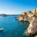 Vue panoramique de la citadelle de Bonifacio perchée sur des falaises blanches surplombant la mer Méditerranée.