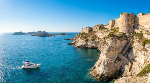Vue panoramique de la citadelle de Bonifacio perchée sur des falaises blanches surplombant la mer Méditerranée.