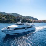 Réserver votre ferry italie corse au meilleur prix Le ferry Mediterranean Voyager naviguant en mer Méditerranée devant un village côtier Corse sous un ciel bleu.